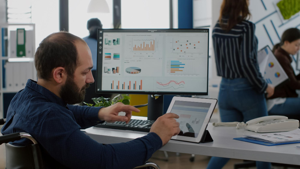 Un hombre concentrado en el análisis de Datos , concentrado trabajando en su estación con múltiples pantallas mostrando gráficos y estadísticas complejas.