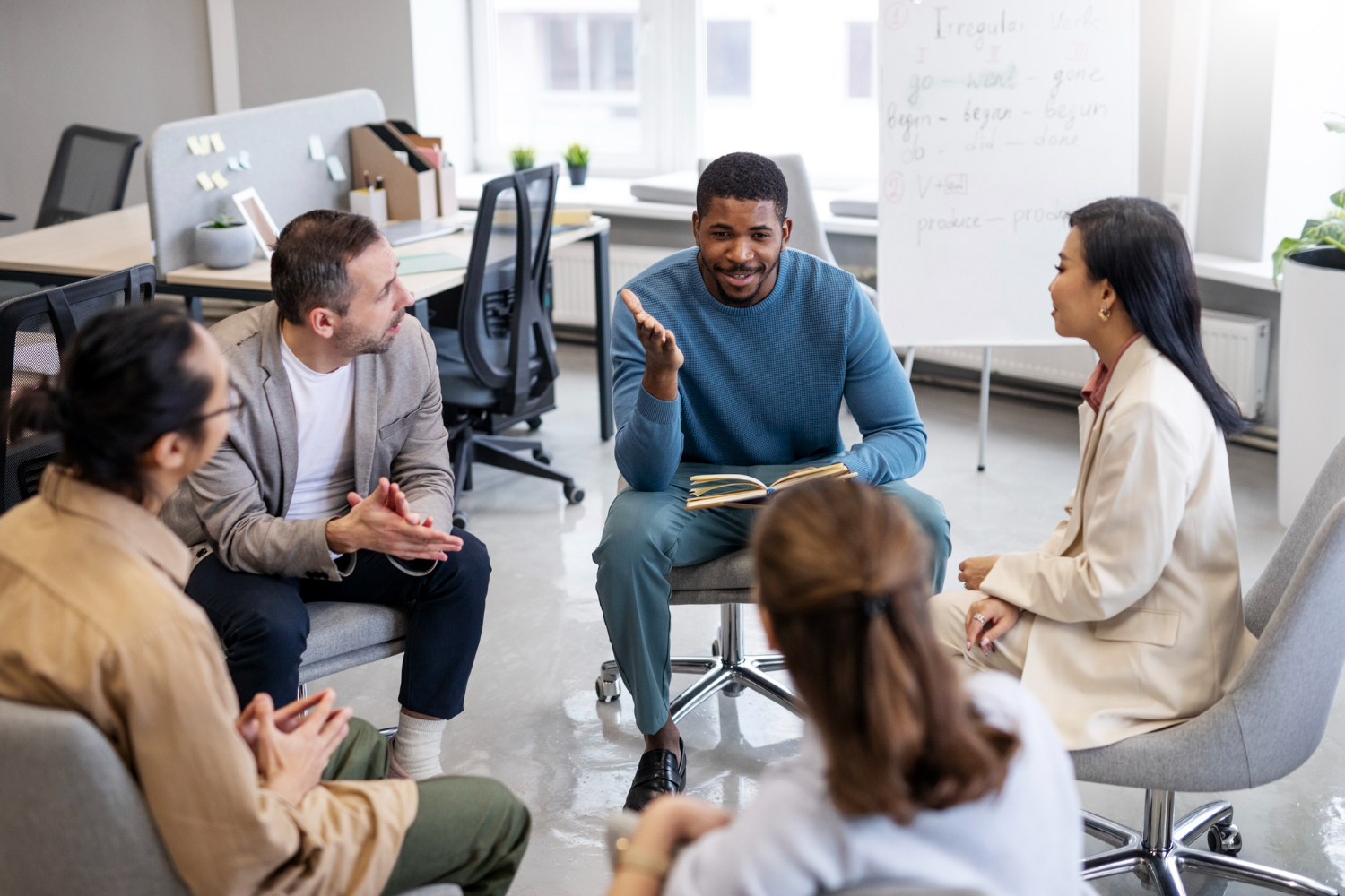 Un grupo diverso de profesionales participa en una discusión de equipo, practicando la escucha activa en una oficina iluminada.