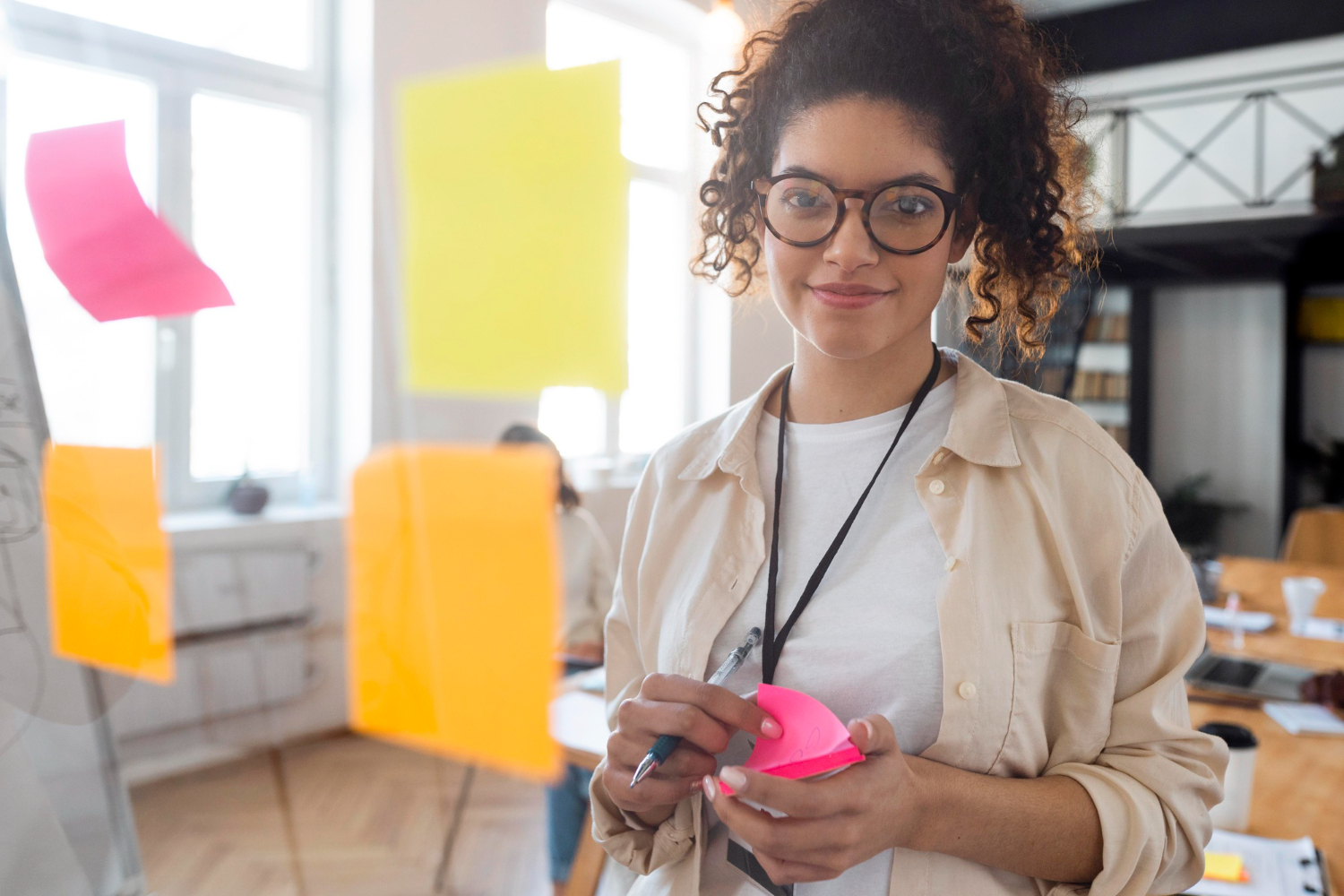 Una mujer empresaria con gafas desarrollando su marca personal mediante una sesión de brainstorming con notas adhesivas.